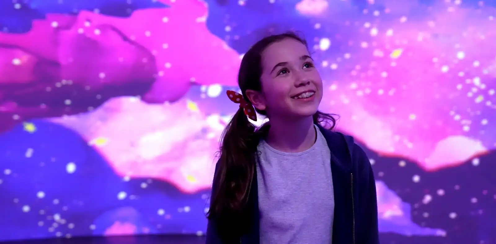 Young girl watching an immersive light show at an interactive exhibition.
